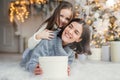 Happy female model with short dark hair and her adorabe small girl have fun together, celebrate Christmas, exchange presents, have Royalty Free Stock Photo