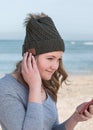 Happy female model wearing green knitted beanie with Bluetooth speakers