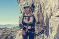 Happy female mountaineer climbing via ferrata.