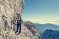 Happy female mountaineer climbing via ferrata.