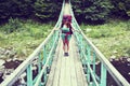 Happy female mountaineer standing on a wooden bridge over a mountain stream overflowing with excitement with the glory and beauty Royalty Free Stock Photo