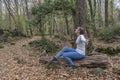 Happy female with open arms and stylish jeans fashion sitting on a tree in the forest.Celebration and happiness concept.Travel