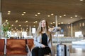 Happy female person sitting in airport hall with modern tablet near valise and showing thumbs up. Royalty Free Stock Photo