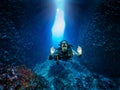 A scuba diver shows the OK sign in front of an underwater cave