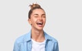 Happy female student with bun hairstyle smiling positively and being in great mood while standing over white studio background. Royalty Free Stock Photo