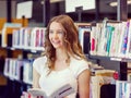 Happy female student holding books at the library Royalty Free Stock Photo