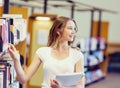 Happy female student holding books at the library Royalty Free Stock Photo