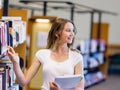 Happy female student holding books at the library Royalty Free Stock Photo