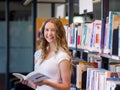 Happy female student holding books at the library Royalty Free Stock Photo