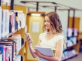 Happy female student holding books at the library Royalty Free Stock Photo