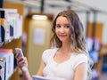 Happy female student holding books at the library Royalty Free Stock Photo