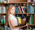 Happy female student with laptop in library Royalty Free Stock Photo