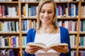 Happy female student reading a book in the library Royalty Free Stock Photo