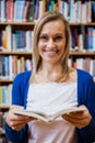 Happy female student reading a book in the library Royalty Free Stock Photo