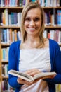 Happy female student reading a book in the library Royalty Free Stock Photo