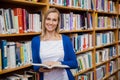 Happy female student reading a book in the library Royalty Free Stock Photo