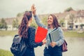 Happy Female students giving five to each other during friendly collaboration on studying project, while standing outdoor Royalty Free Stock Photo