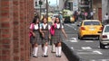 Happy Female Teen Students Walking On Sidewalk