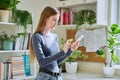 Happy female teenager using smartphone, standing at home Royalty Free Stock Photo