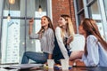 Happy female teenagers sitting on table looking and pointing at stylish light bulbs and relaxing during a recess between
