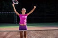 Happy female tennis player jumping near the net and laughing, celebrating her winning in tennis match. Sport, health Royalty Free Stock Photo