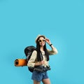 Happy female tourist with backpack on light blue background Royalty Free Stock Photo