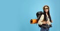 Happy female tourist with backpack on light blue background. Space for text Royalty Free Stock Photo