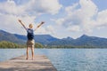Happy female traveler with backpack raising arms, tropical travel destination Royalty Free Stock Photo