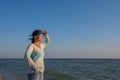 Happy female traveler stands alone on the sea coast Royalty Free Stock Photo