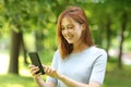 Happy female using smart phone walking in a park Royalty Free Stock Photo