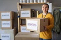 Happy female volunteer looking at camera. Woman organizes food and clothing drive. She is holding a donation box. People Royalty Free Stock Photo