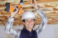 Happy female worker drilling ceiling Royalty Free Stock Photo