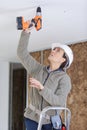 happy female worker drilling ceiling