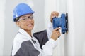 Happy female worker sanding wall Royalty Free Stock Photo