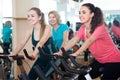 Happy females of different age training on exercise bikes