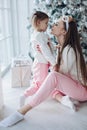 Happy festive mother and daughter hugging sitting together at decorating beautiful Christmas tree Royalty Free Stock Photo