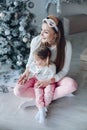 Happy festive mother and daughter hugging sitting together at decorating beautiful Christmas tree Royalty Free Stock Photo