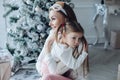 Happy festive mother and daughter hugging sitting together at decorating beautiful Christmas tree Royalty Free Stock Photo