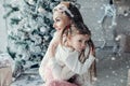 Happy festive mother and daughter hugging sitting together at decorating beautiful Christmas tree Royalty Free Stock Photo
