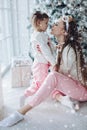 Happy festive mother and daughter hugging sitting together at decorating beautiful Christmas tree Royalty Free Stock Photo