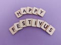 Happy festivus message written on wood blocks on a purple background