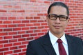 A happy Filipino professional with a confident look ( on a red brick wall)