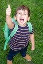 Happy first day of elementary school. Little boy with backpack showing thumbs up