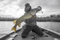 Happy fisherman with big pike fish trophy at the boat with fishing tackles Royalty Free Stock Photo