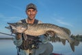 Happy fisherman with big pike fish trophy at the boat with fishing tackles Royalty Free Stock Photo