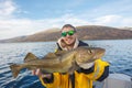 Happy fisherman with cod fish in hands Royalty Free Stock Photo