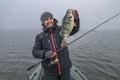 Happy fisherman hold big perch fish at boat with tackle. Success fishing at wild lake Royalty Free Stock Photo