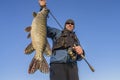 Happy fisherman holding big pike fish trophy and fishing rod Royalty Free Stock Photo