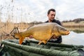 Fisherman holding a huge carp at the lake