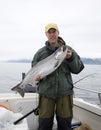 Happy fisherman in holds big silver salmon